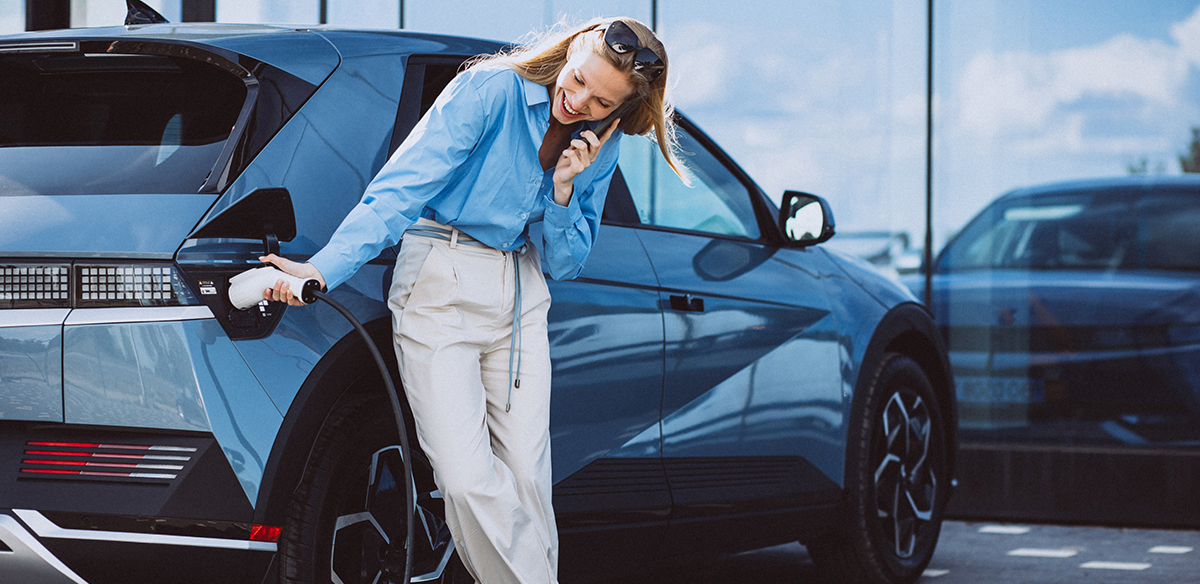 Photograph of a young woman electrically charging her hybrid car.